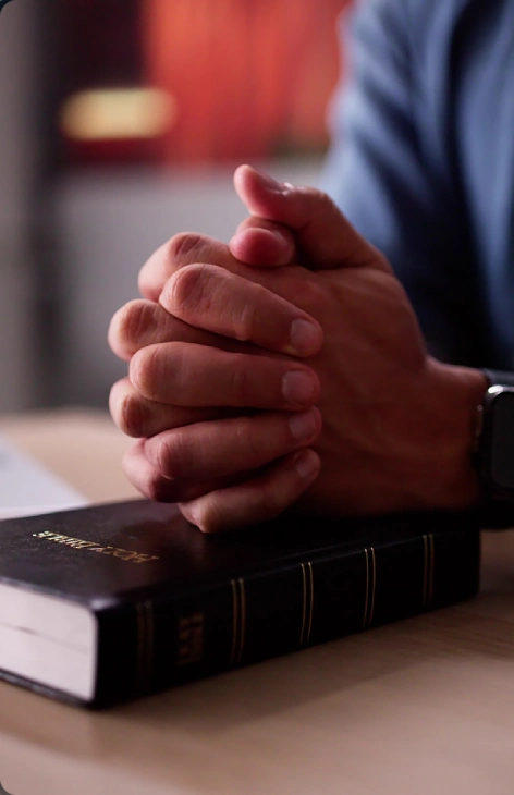 Hands clasped over a closed book.