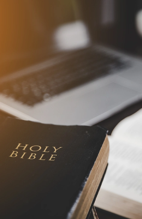 Bible and laptop on a desk.